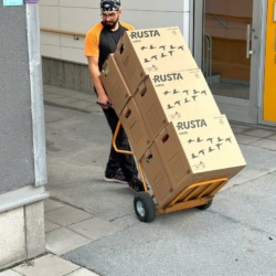 Medarbetare från Scandiflytt kör flyttkartonger med en kärra under en flytt.